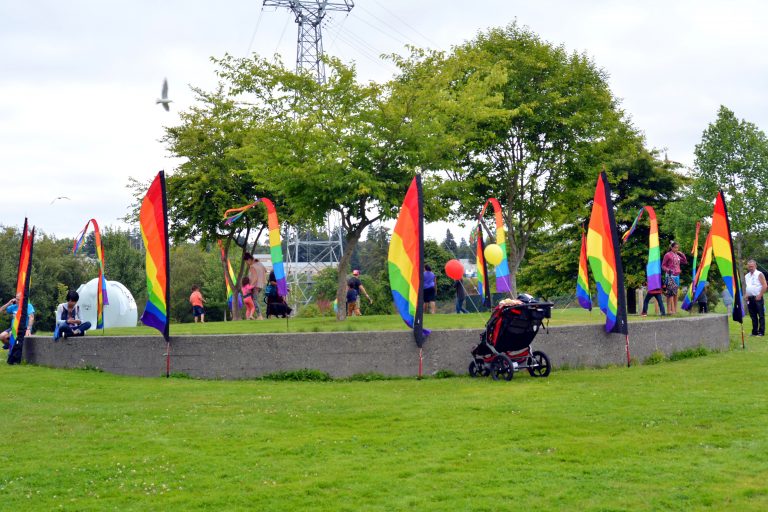 Rainbow flags wave as visitors mill about during the 2016 Kitsap Pride festival. (Kitsap Scene File Photo). File photo showing rainbow flags waving during the 2016 Kitsap Pride event.
