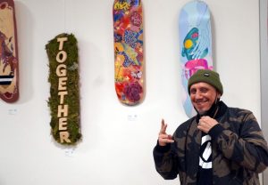 Urbanist Collective Executive Director Erik Gonzalez poses in front of some of the selected pieces at the All Hands on Deck skateboard art show. (Photo by Kitsap Scene) Urbanist Collective Executive Director Erik Gonzalez poses in front of some of the selected pieces at the All Hands on Deck skateboard art show.