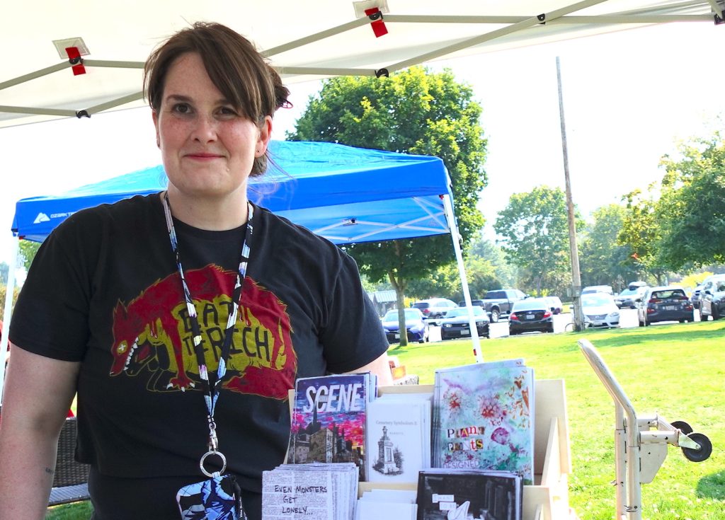 Bremerton Zine & Small Press Festival organizer and founder Dani Gray poses in front of her booth with several zines on display. Photo by Kitsap Scene.