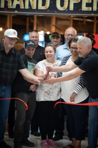 Greg Randall, far right, and Julie Randall, second from right, cut the ribbon on their axe-throwing business, PenAxe. (Photo courtesy of PenAxe).