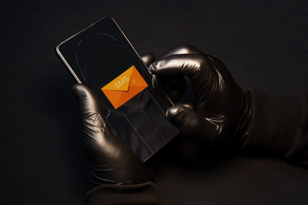 A cybercriminal sending fraudulent text messages via cell phone to scam vulnerable people.