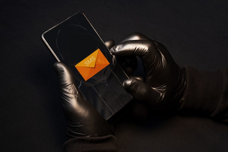 A cybercriminal sending fraudulent text messages via cell phone to scam vulnerable people.