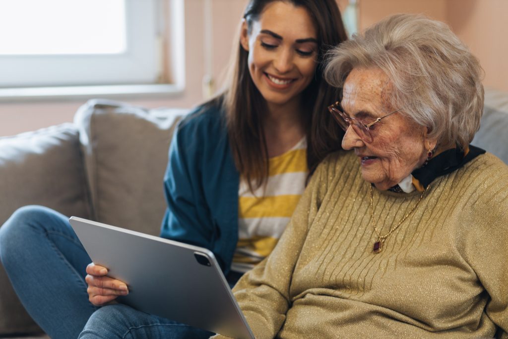 Washington state ranked high for its support of family caregivers in a new report. (Studio Dva Kera/Adobe Stock) Nurse visiting a senior woman, showing her news online.