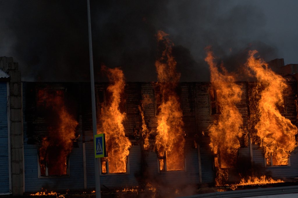 Fire fighters try to save a home from forest fire as flames rapidly approach the house.