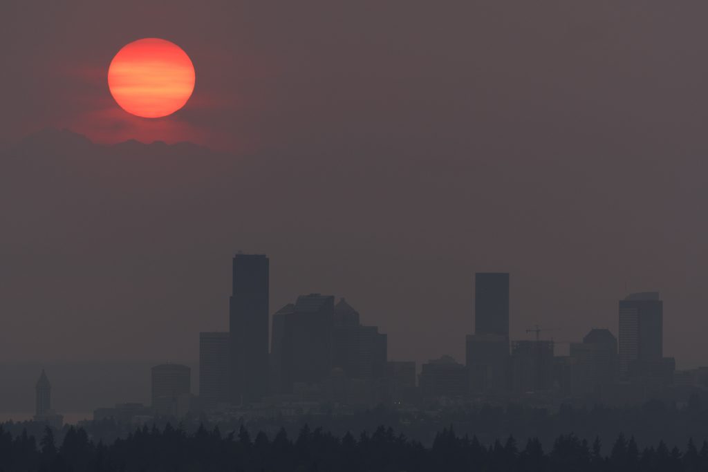 A red sun obscured by wildfire smoke over the city of Seattle
