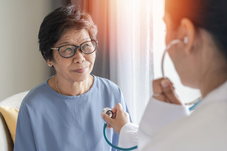 Happy elderly patient with medical health checkup with cardiologist or geriatric doctor. Senior old aging woman with coronary artery heart disease or cardiac illness check-up in clinic