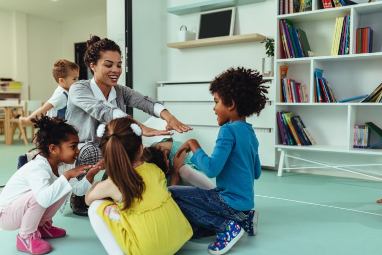 Teacher is playing with cheerful children at kindergarten